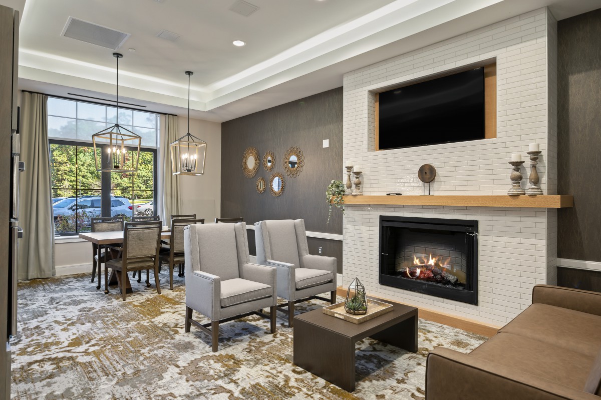 A modern living room with a fireplace and dining area, featuring comfortable seating and elegant lighting.