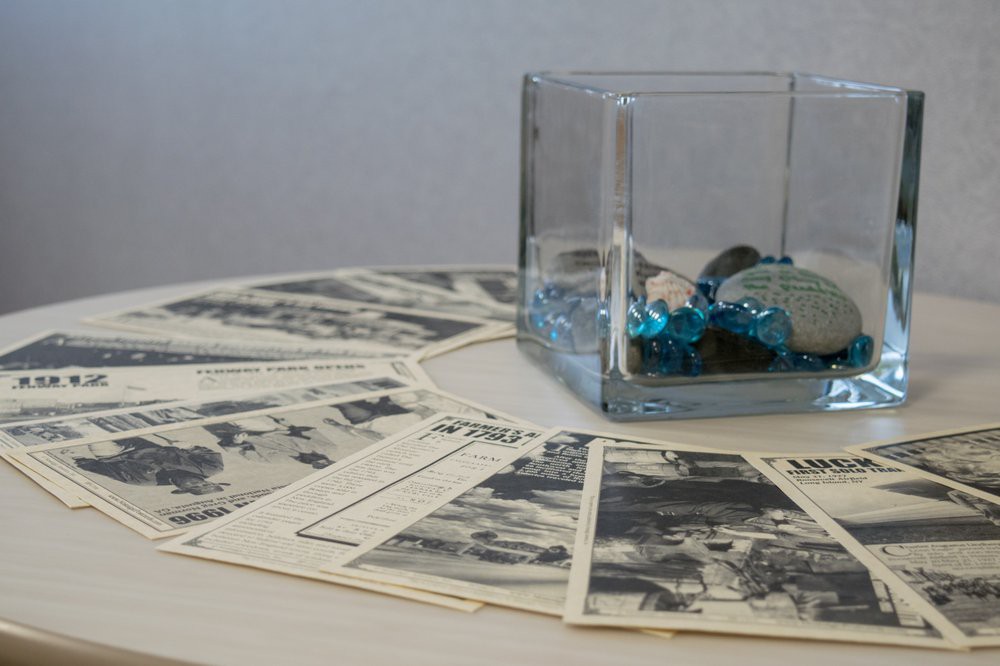 A decorative arrangement featuring vintage photographs spread out in a circle with a glass container filled with blue ornaments at the center.