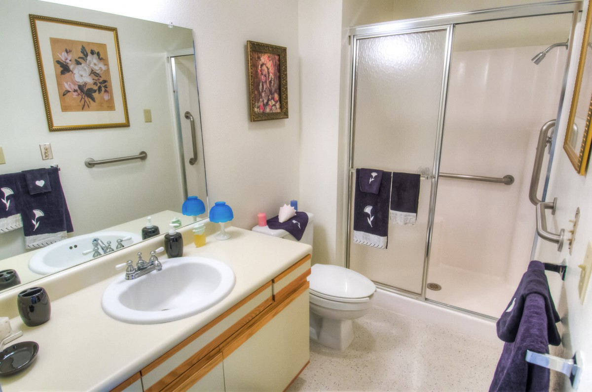 A well-organized bathroom with a sink, mirror, and shower.