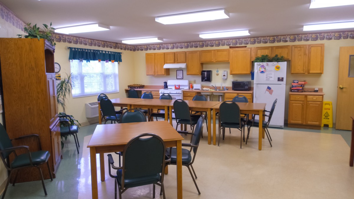 An indoor kitchen and dining area with tables, chairs, and appliances.