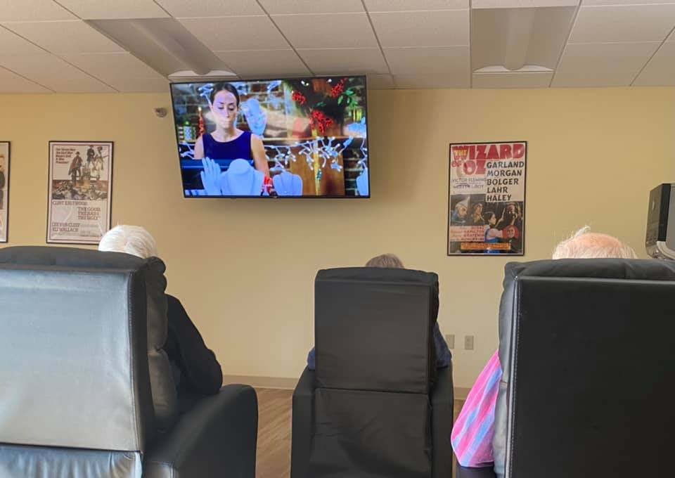 People sitting in a waiting room, watching television.