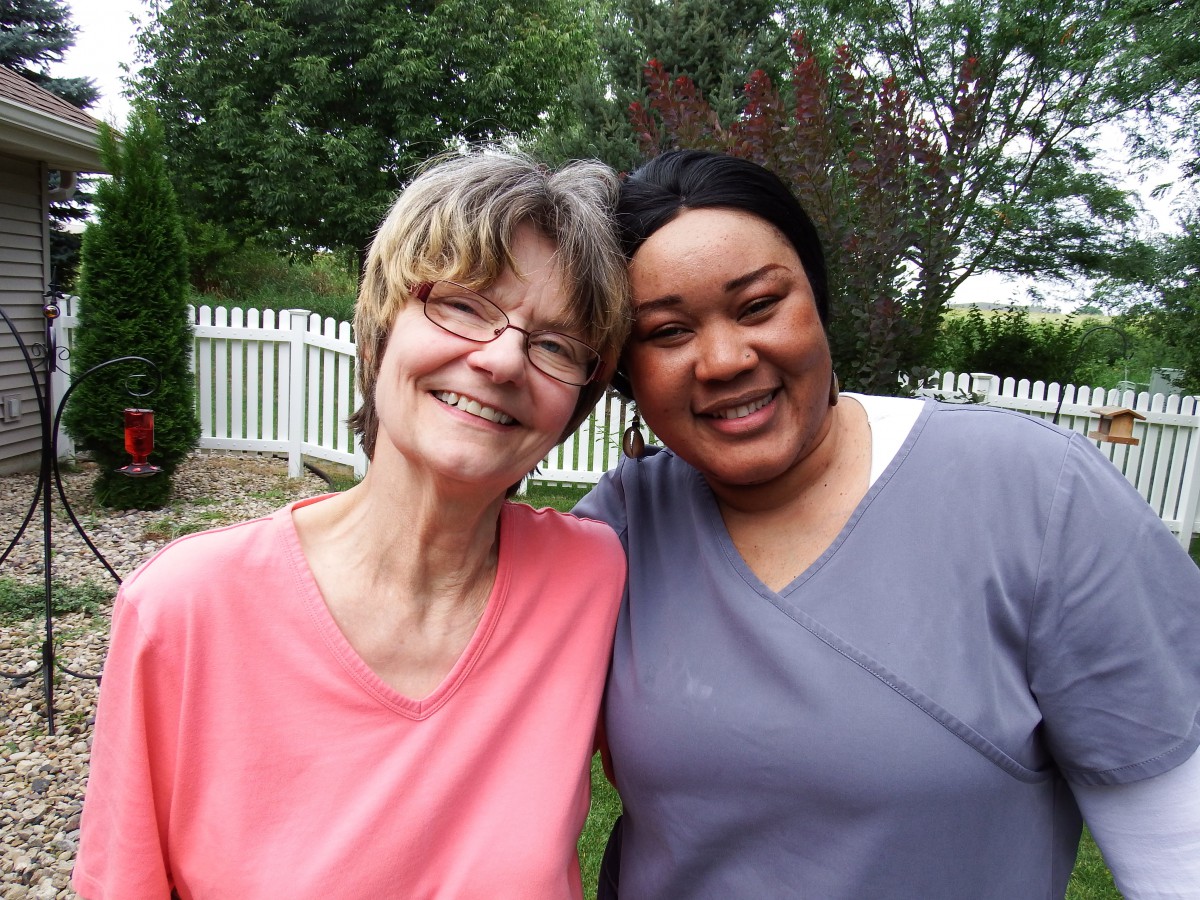 Two people smiling and posing together in a garden setting.