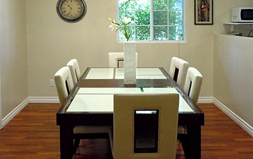 A modern dining room with a glass-top table, six chairs, and a decorative vase.