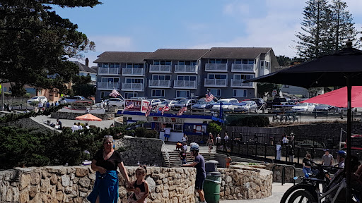 A sunny day at the beach with a family enjoying the outdoor atmosphere near a hotel adorned with flags.