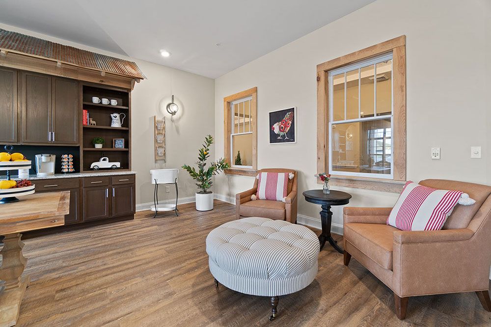 A cozy living room with stylish decor, featuring wood flooring, comfortable armchairs, and a central ottoman.