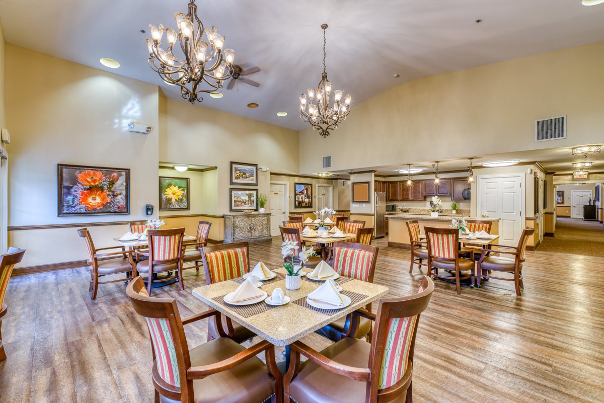 A well-decorated dining area with tables set for guests, featuring chandeliers and elegant furnishings.