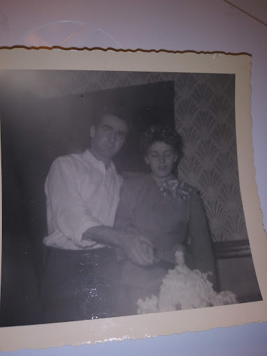 A vintage black and white photo capturing a couple celebrating with a cake.