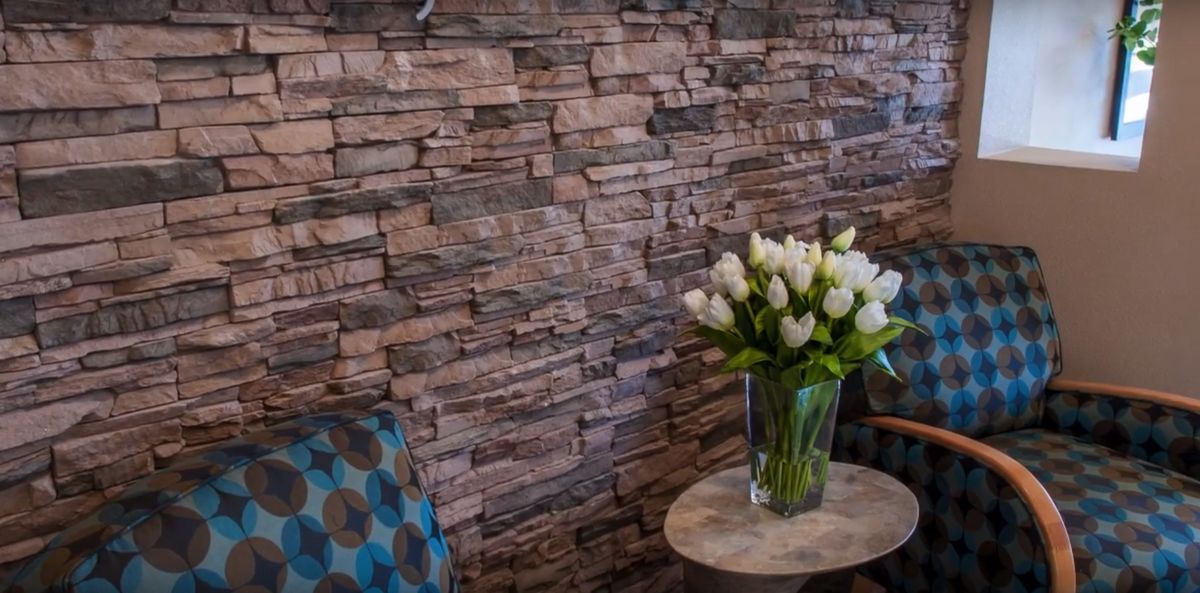 A cozy interior with a stone wall and a vase of white tulips on a small table.