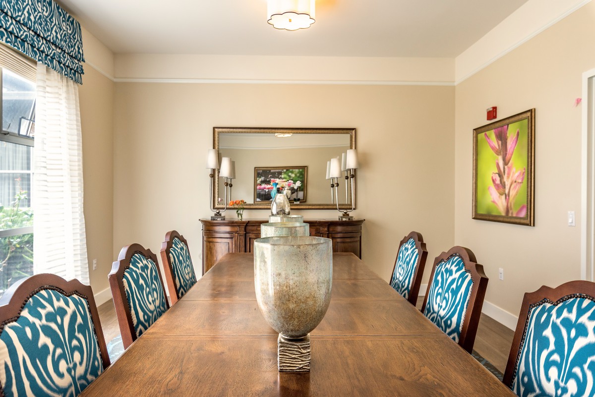 An elegant dining room with a long wooden table, patterned chairs, and decorative vases.