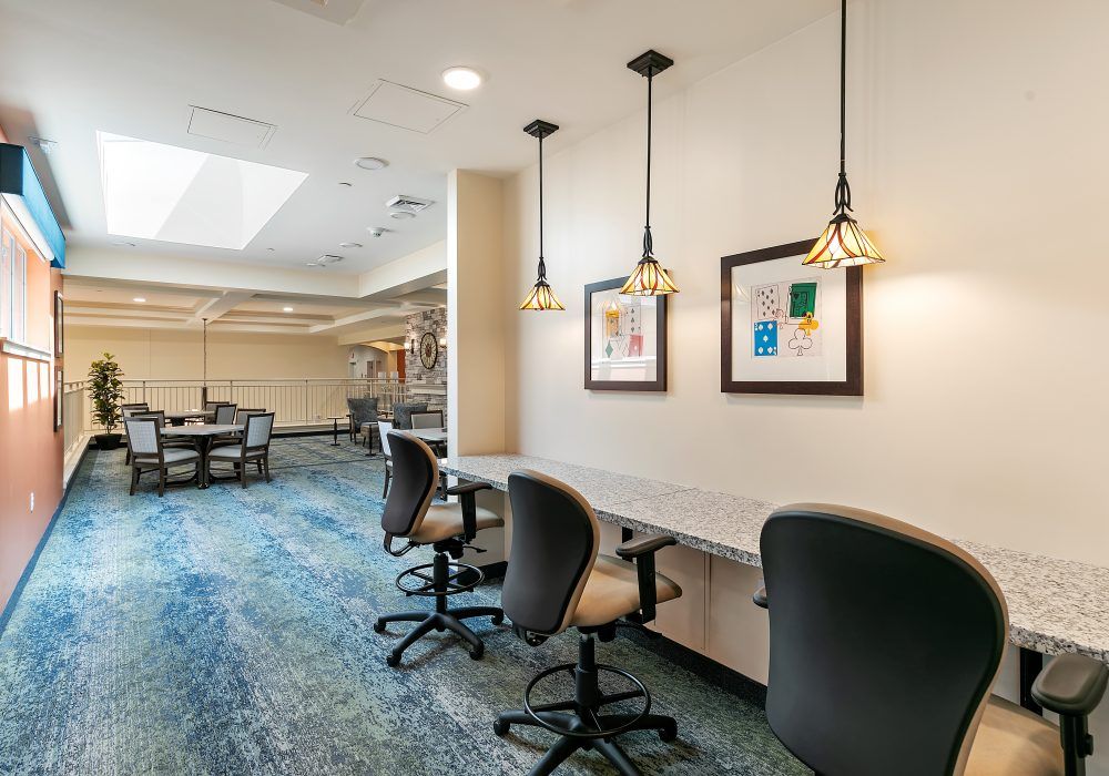 A modern office space featuring a row of desks with chairs and pendant lighting.