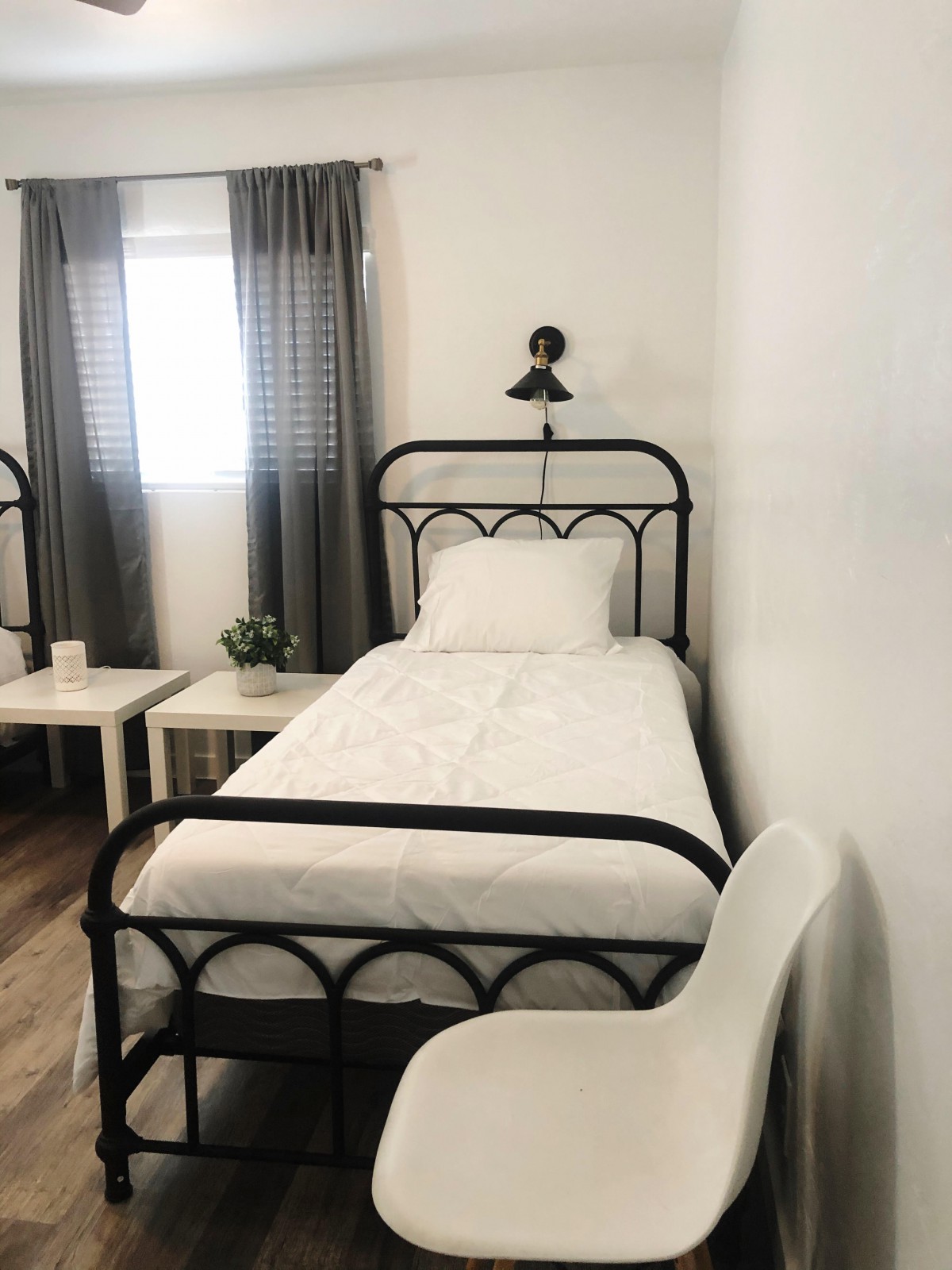 A minimalist bedroom with a single black metal framed bed and white bedding, complemented by a modern decor style.