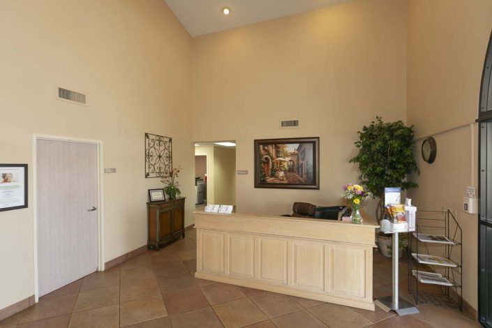 A spacious reception area with a desk, artwork, and plants.