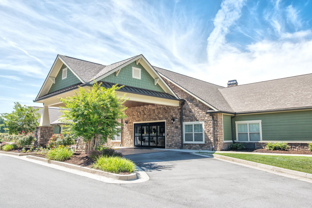 A picturesque residential building with a welcoming entrance and well-maintained landscaping under a partly cloudy sky.