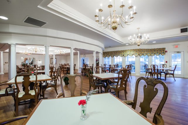 An elegant dining area featuring chandeliers and neatly arranged tables and chairs.