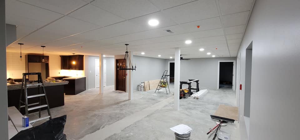A basement under renovation with exposed concrete floors and partially finished walls.