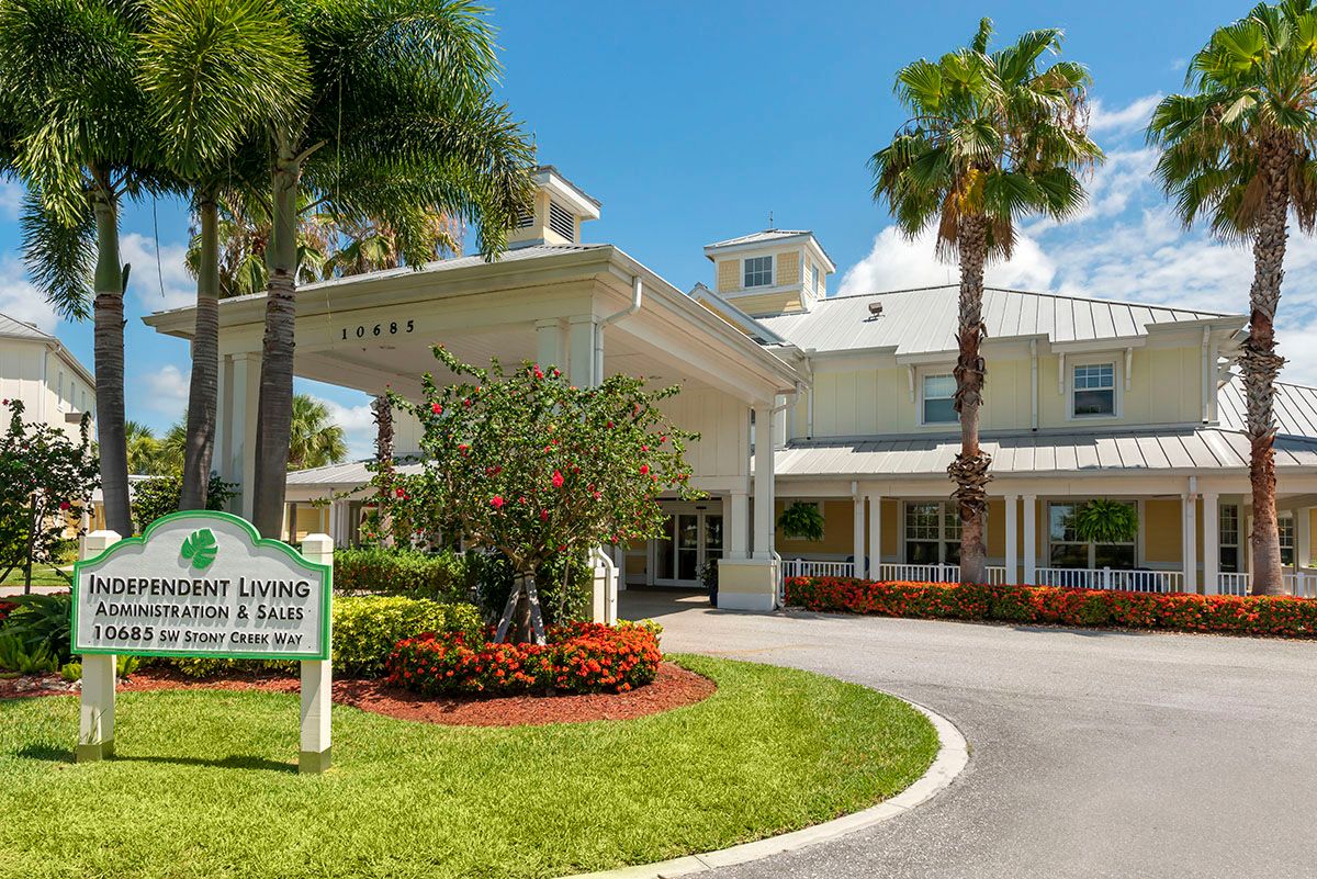 A sunny view of a landscaped building entrance with palm trees.