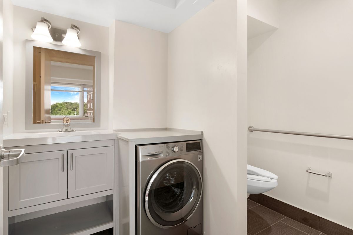 A modern laundry room with a washing machine and a sink.