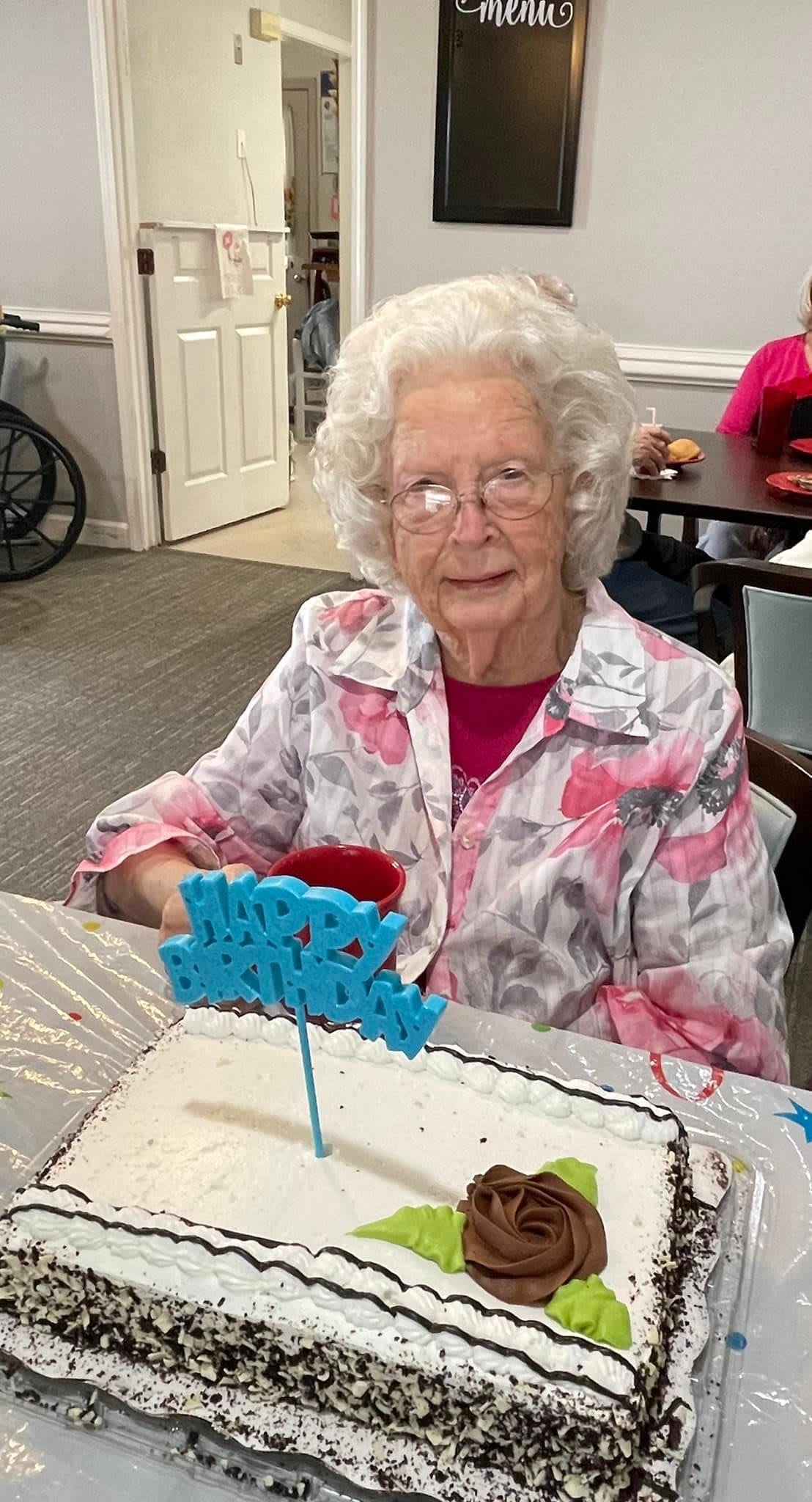 An elderly woman celebrating her birthday with a cake.