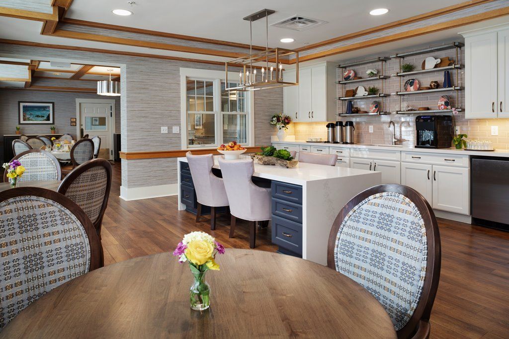 A modern kitchen and dining area featuring a central island, stylish chairs, and wood flooring.