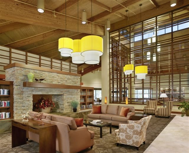 A modern living room with a cozy atmosphere, featuring wood accents and vibrant yellow pendant lights.