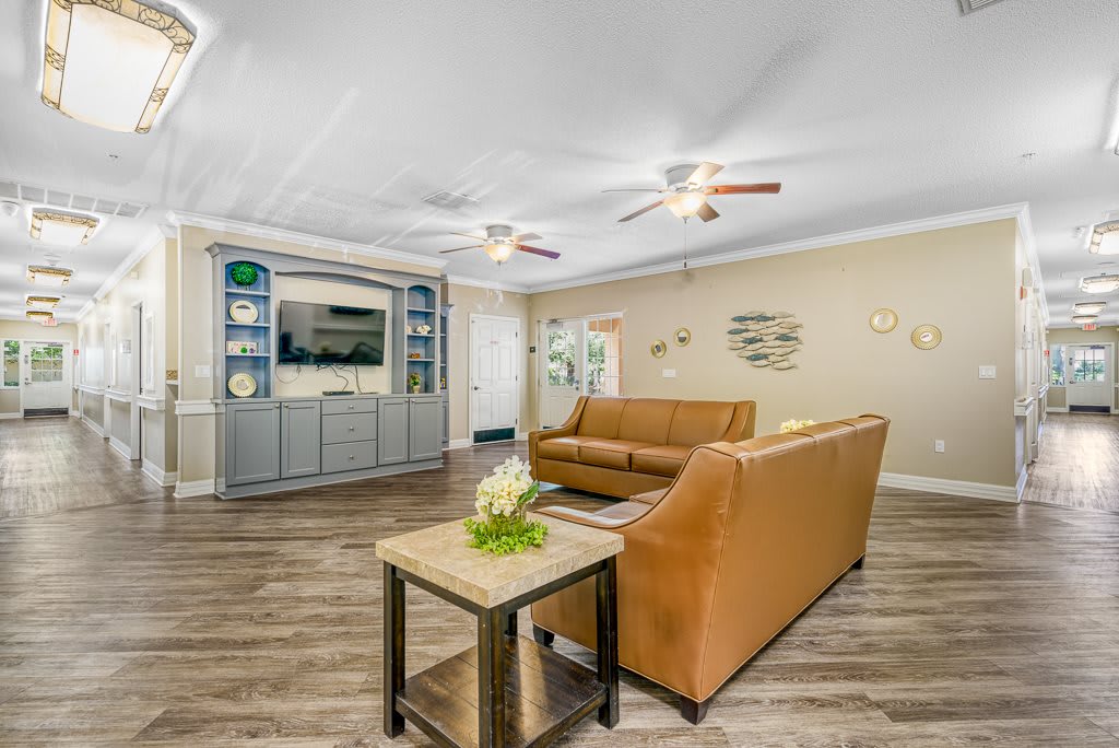 A modern living room with a brown sofa, coffee table, and entertainment center featuring a television, all set on wooden flooring.