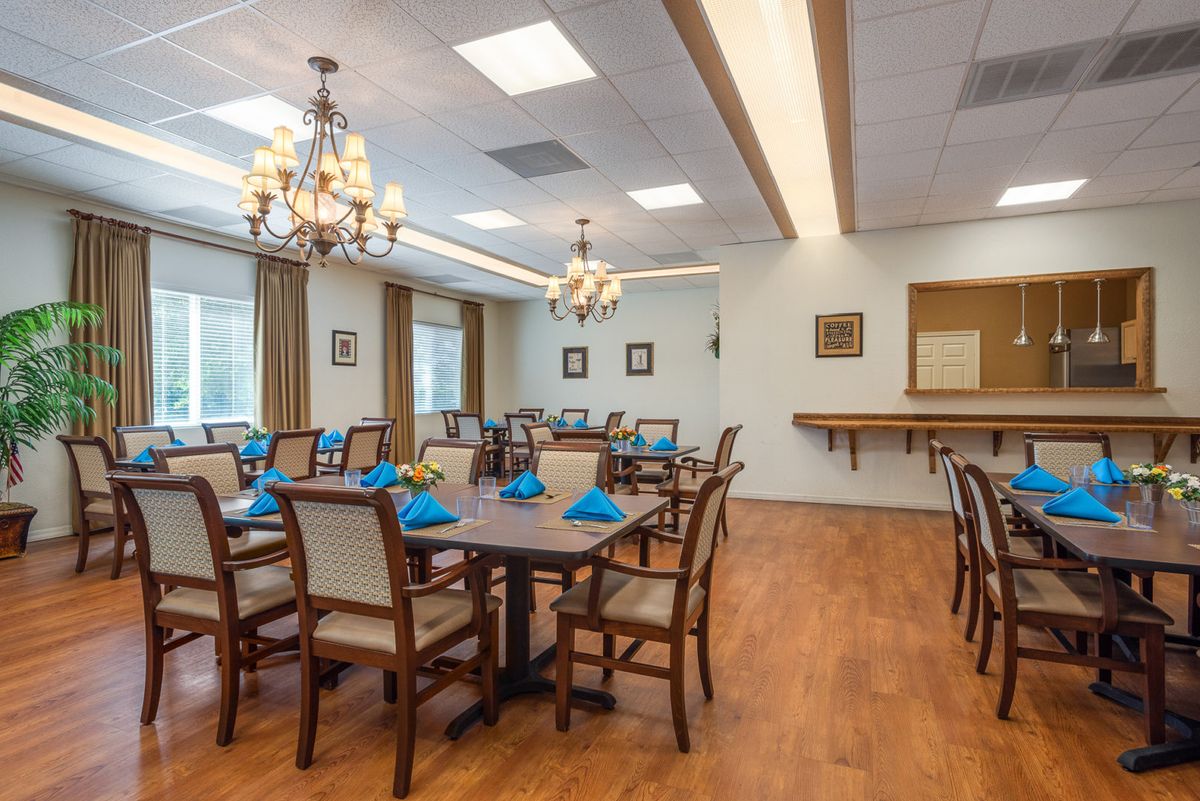 An elegantly decorated dining room with chandeliers, featuring neatly arranged tables and chairs.