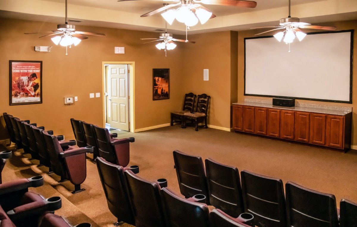 A home theater setup with multiple rows of chairs facing a large projector screen.