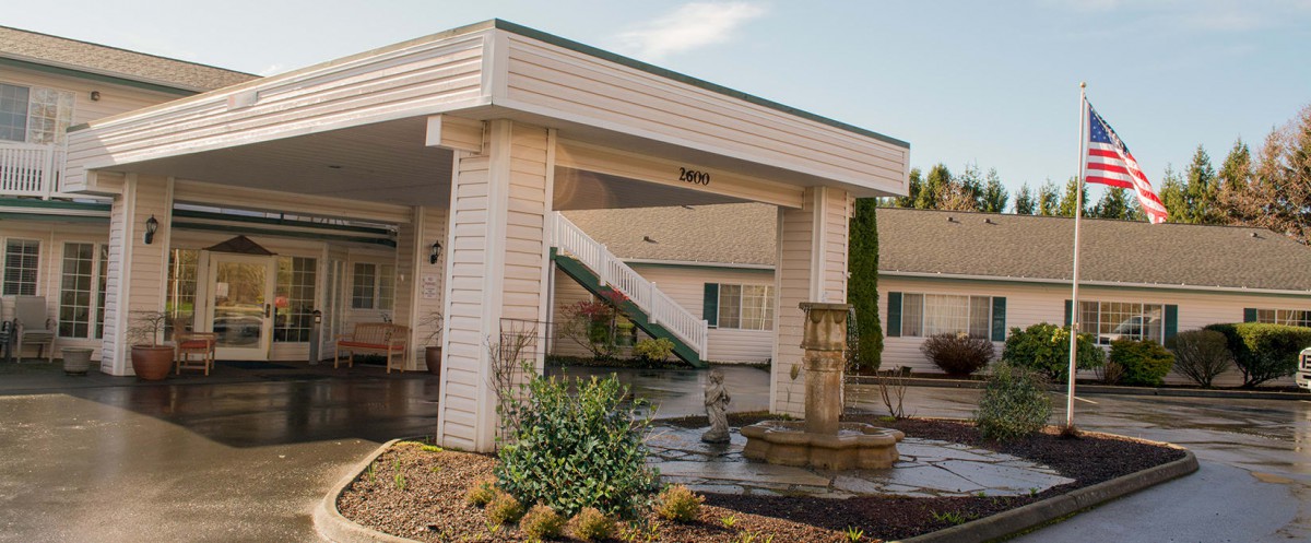 The entrance of a motel featuring a small fountain and landscaped area.