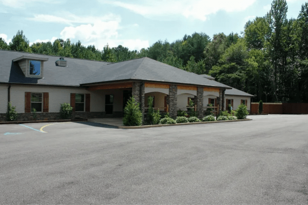 A residential building with a landscaped driveway and surrounding trees.