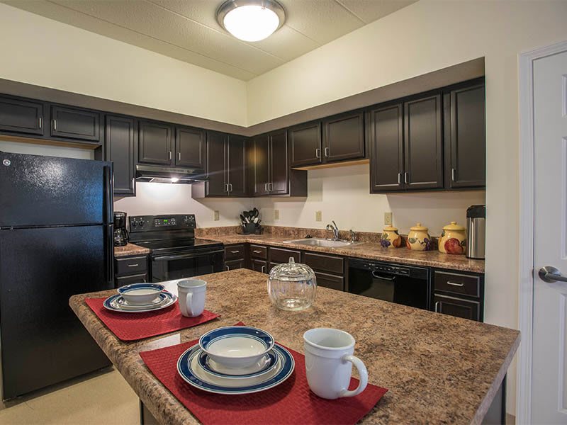 A modern kitchen with dark cabinets, appliances, and a set dining area on the countertop.