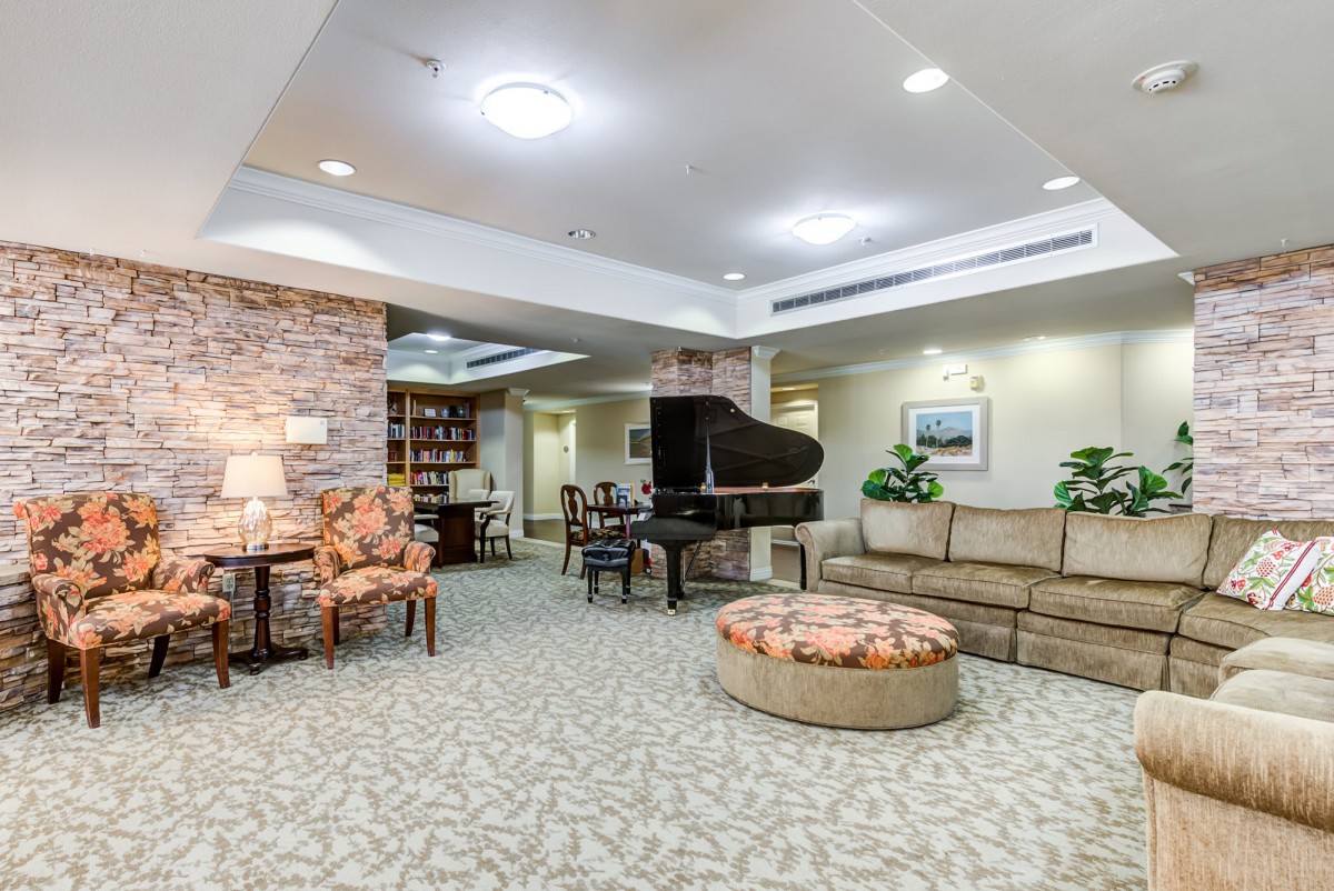 A spacious and cozy lobby area featuring comfortable seating, a grand piano, and warm lighting.