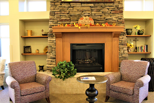 A cozy living room setting featuring a stone fireplace, comfortable armchairs, and autumn-themed dcor.