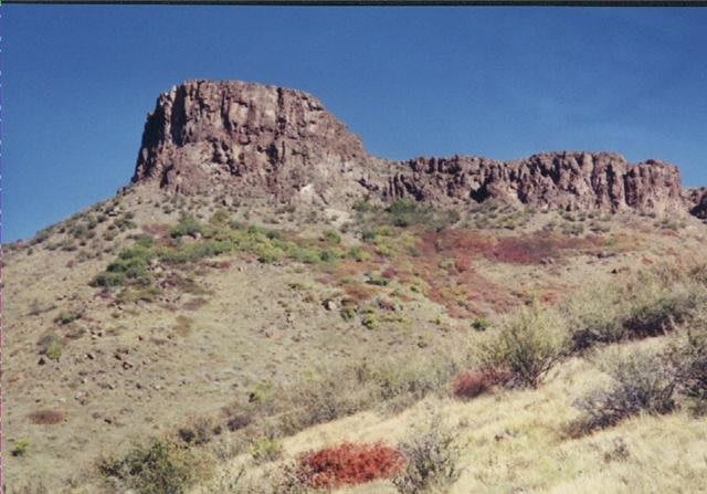 A scenic view of a mesa in a desert landscape under a clear blue sky.