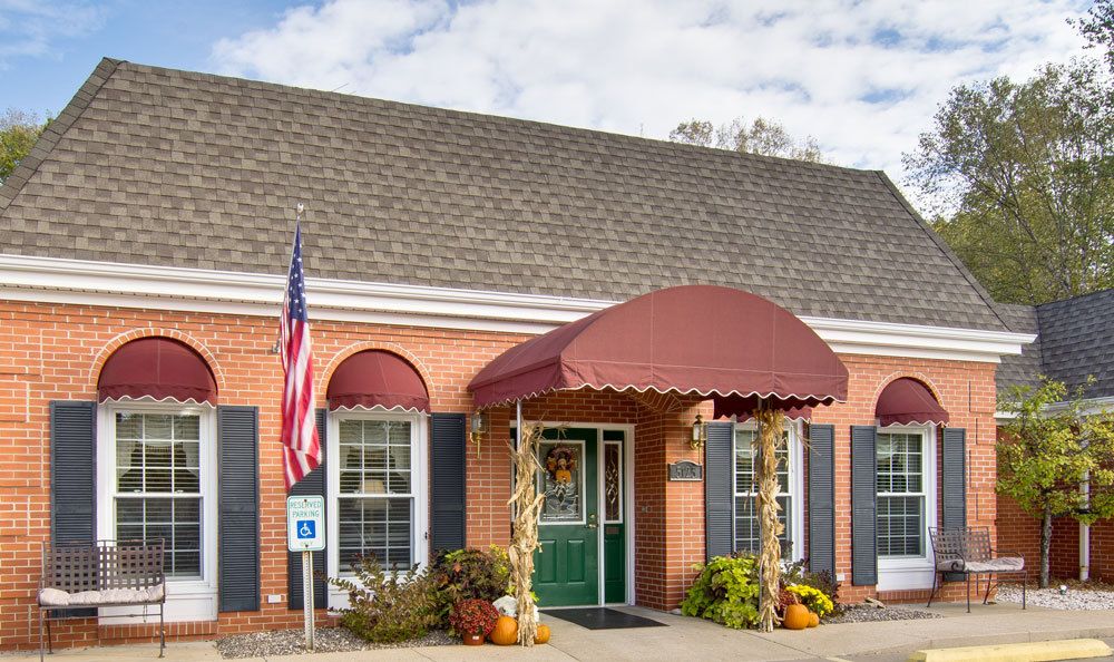 A brick building with a red awning and an American flag, adorned with seasonal decorations at the entrance.