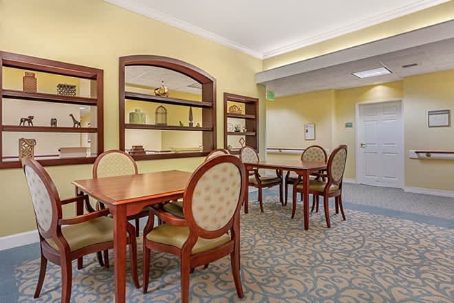 A well-furnished dining room with wooden tables and chairs, featuring elegant decor and carpeting.