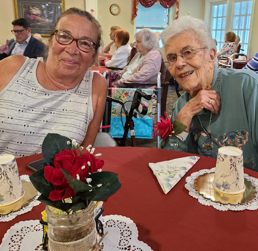 Two joyful women enjoying a social gathering, surrounded by festive decorations.