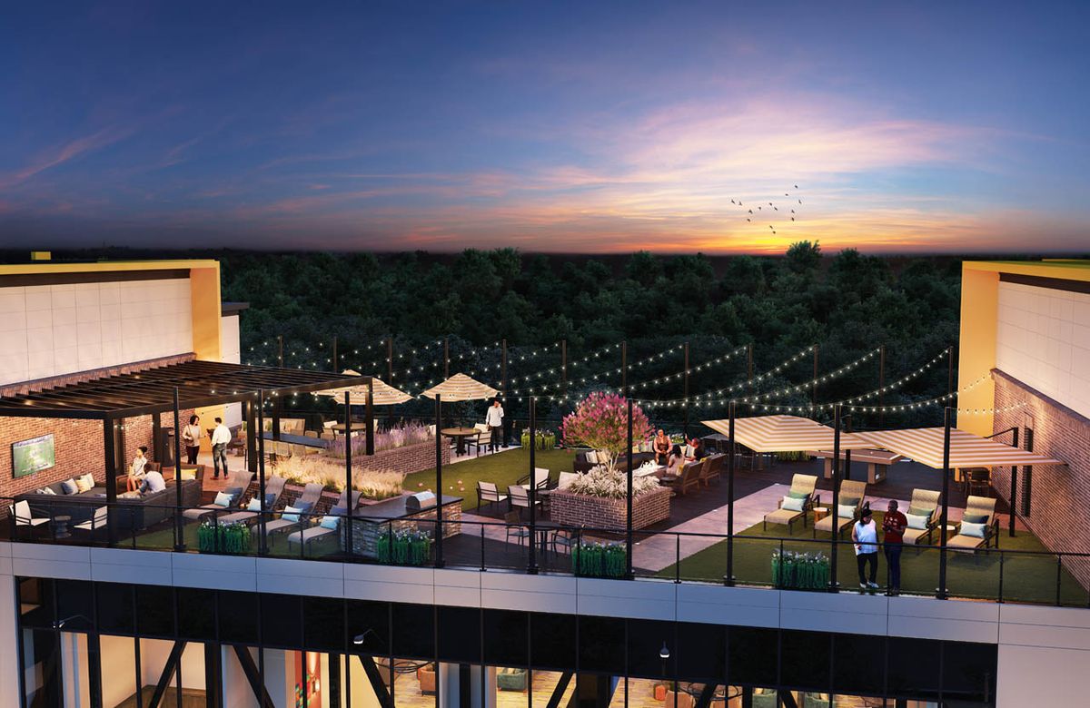 A lively rooftop scene at sunset with cozy outdoor seating and decorative string lights.