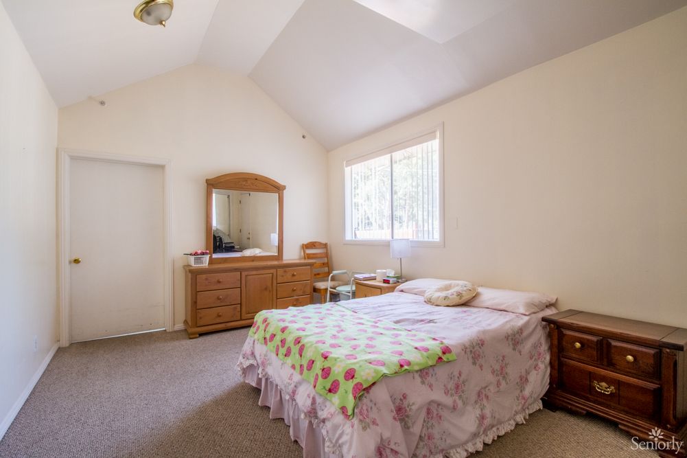 A cozy bedroom with a bed, dresser, and large window.