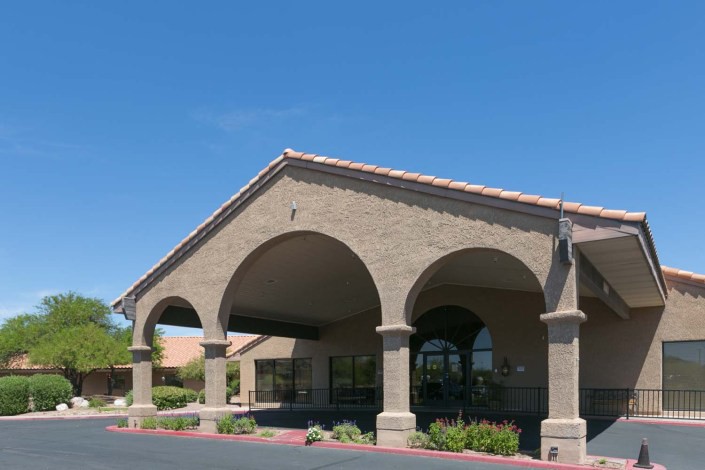 An exterior view of a commercial building with large arched entrances under a clear blue sky.