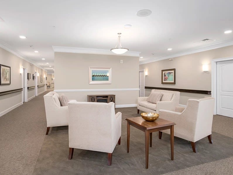 A modern living room with white chairs and a coffee table, featuring neutral decor.