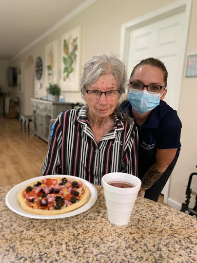 A caregiver and an elderly woman enjoying a meal together.