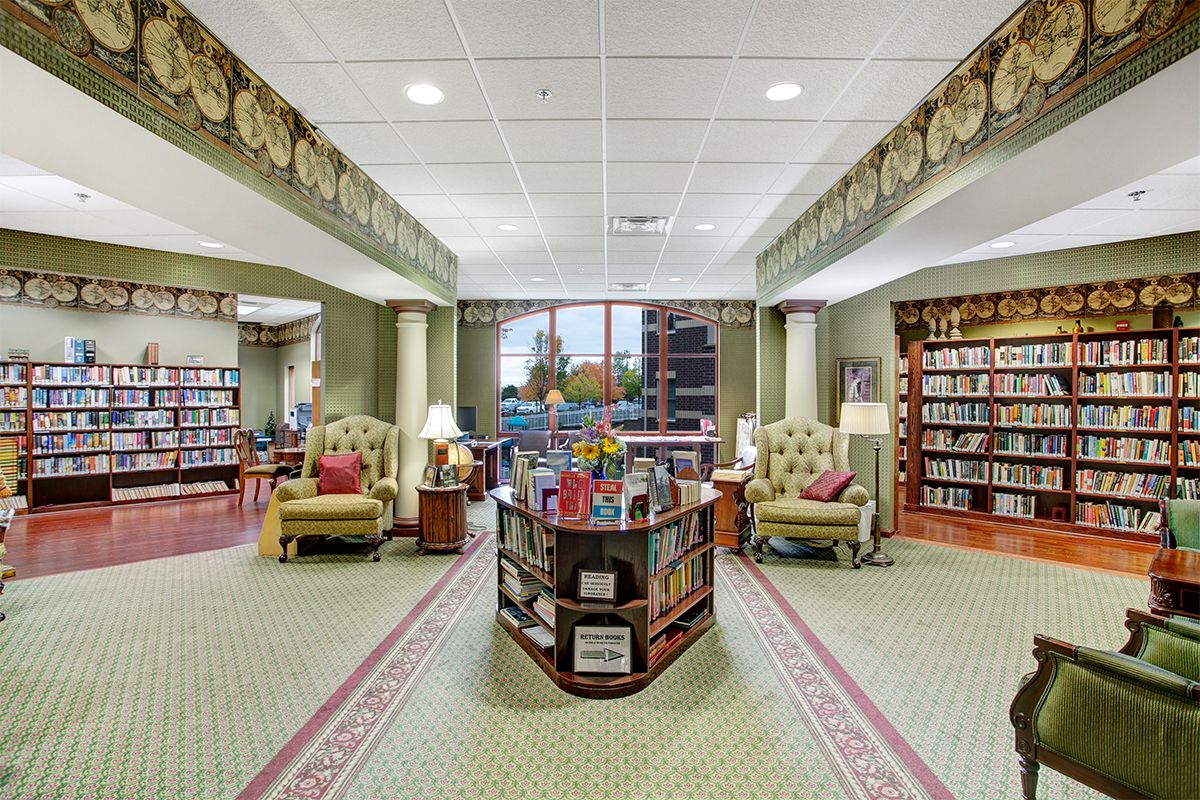 A cozy library interior with book shelves, comfortable seating, and large windows.