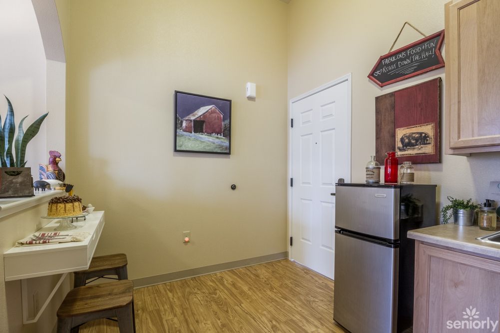 A small kitchen area featuring a refrigerator and wall art.