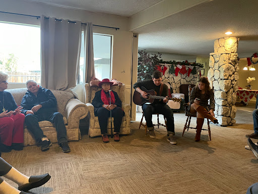 A cozy indoor gathering where friends enjoy music together during the holiday season.