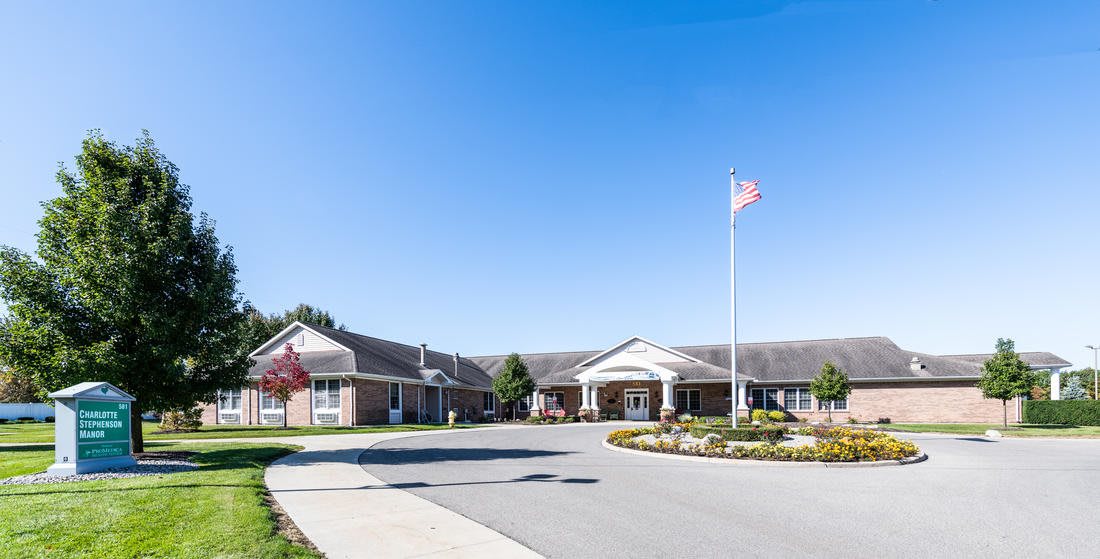 A well-maintained institutional building with a flagpole and clean landscaping under a clear blue sky.