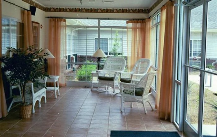 A cozy sunroom with wicker chairs and large glass windows letting in natural light.