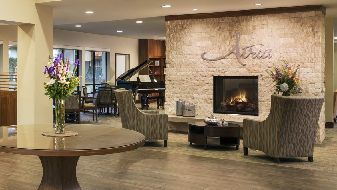 A modern lobby area featuring a fireplace, piano, and comfortable seating.
