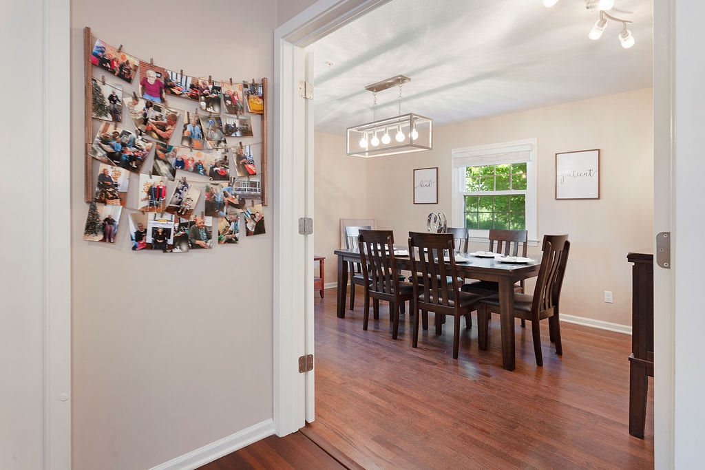A cozy dining room with wooden flooring and a photo collage on the wall.