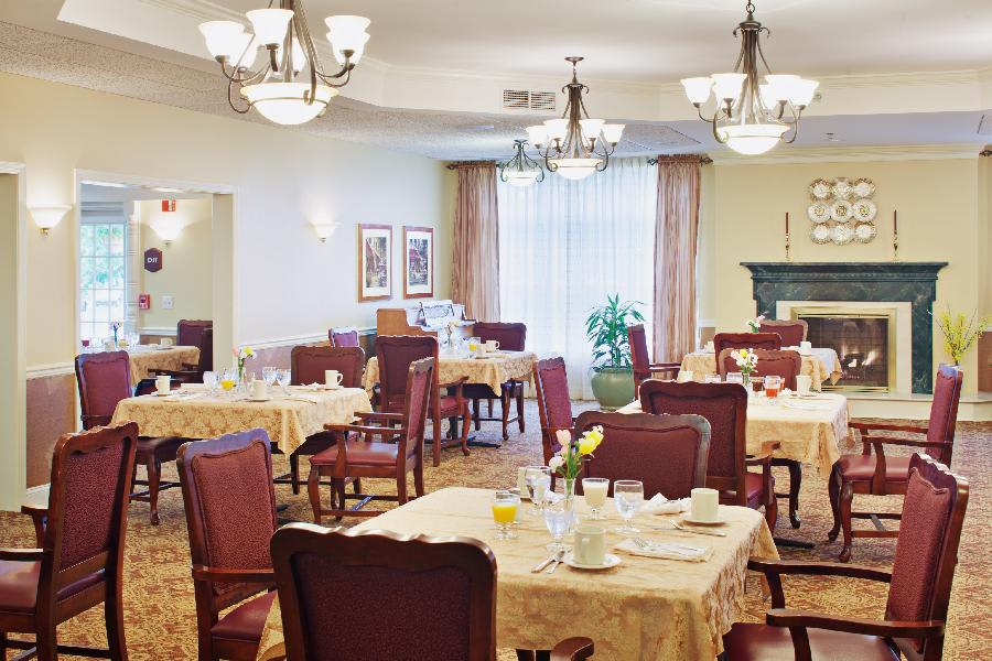 Elegant dining room with neatly arranged tables and chairs, adorned with chandeliers.