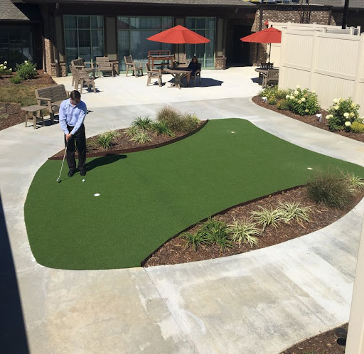A person practicing putting on a well-maintained outdoor putting green.